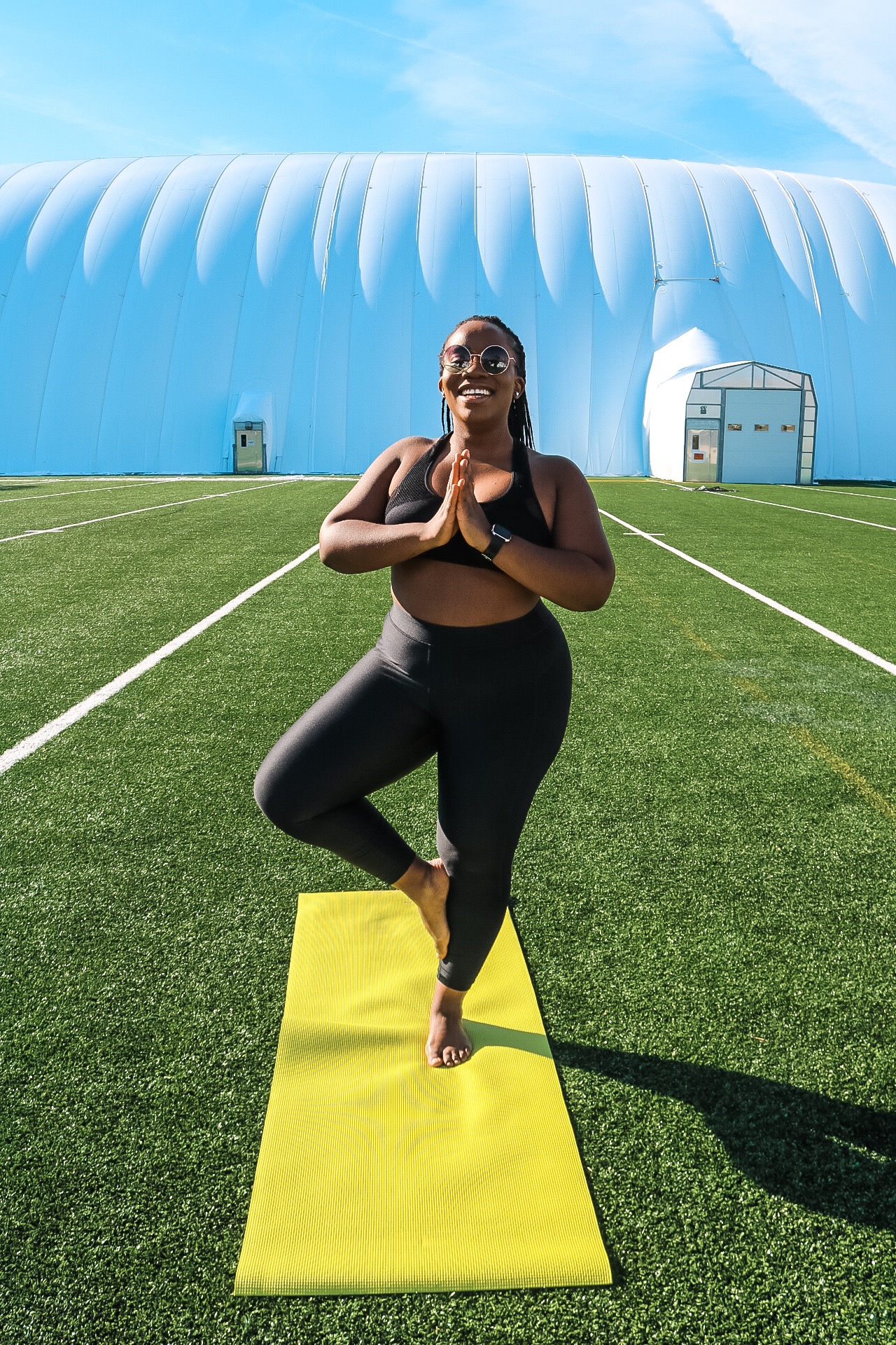 Boston blogger Binja on a yoga mat in a yoga tree pose in under armor workout gear 