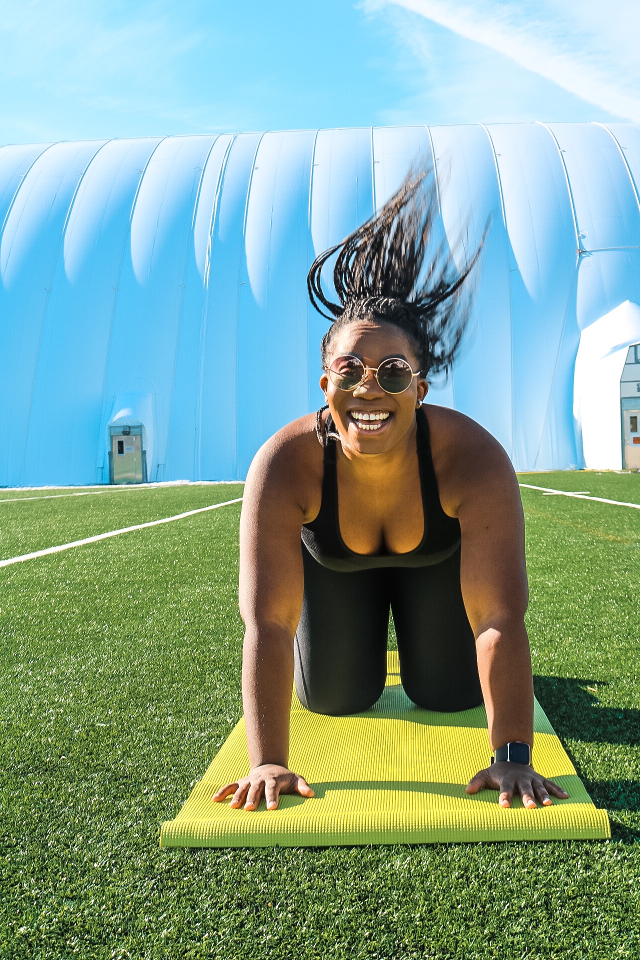 Boston blogger Binja on a yoga mat laughing after a work out in under armor workout gear 