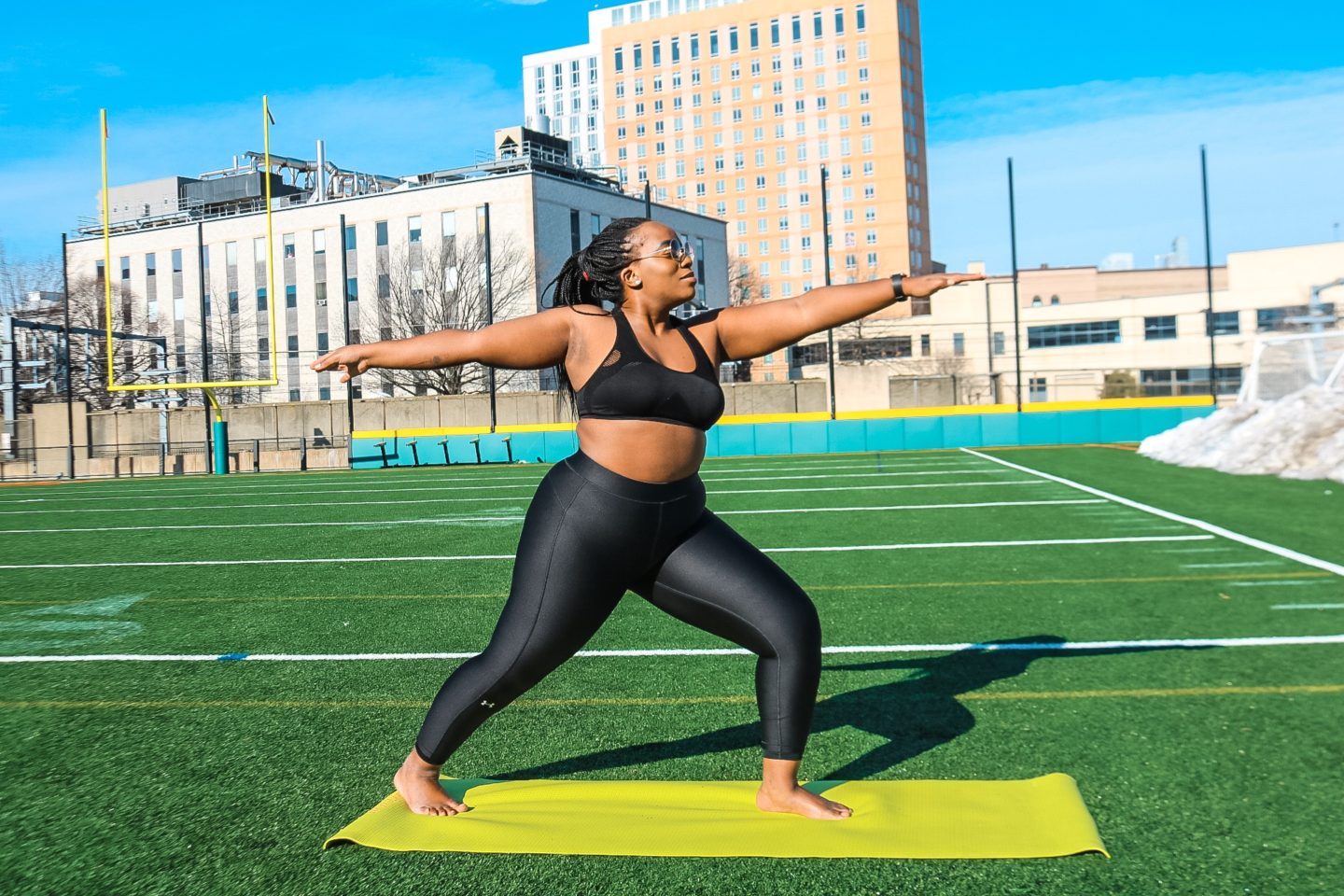 Boston blogger Binja on a yoga mat in easy pose in under armor workout gear 