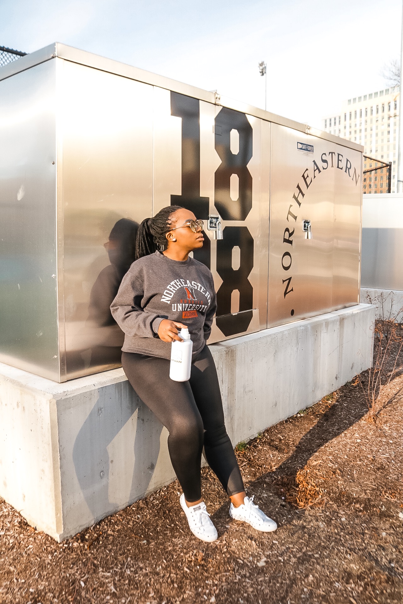 Boston based Fashion and travel blogger Binja in athleisure wear: Northeastern University sweatshirt and reebok workout tights.