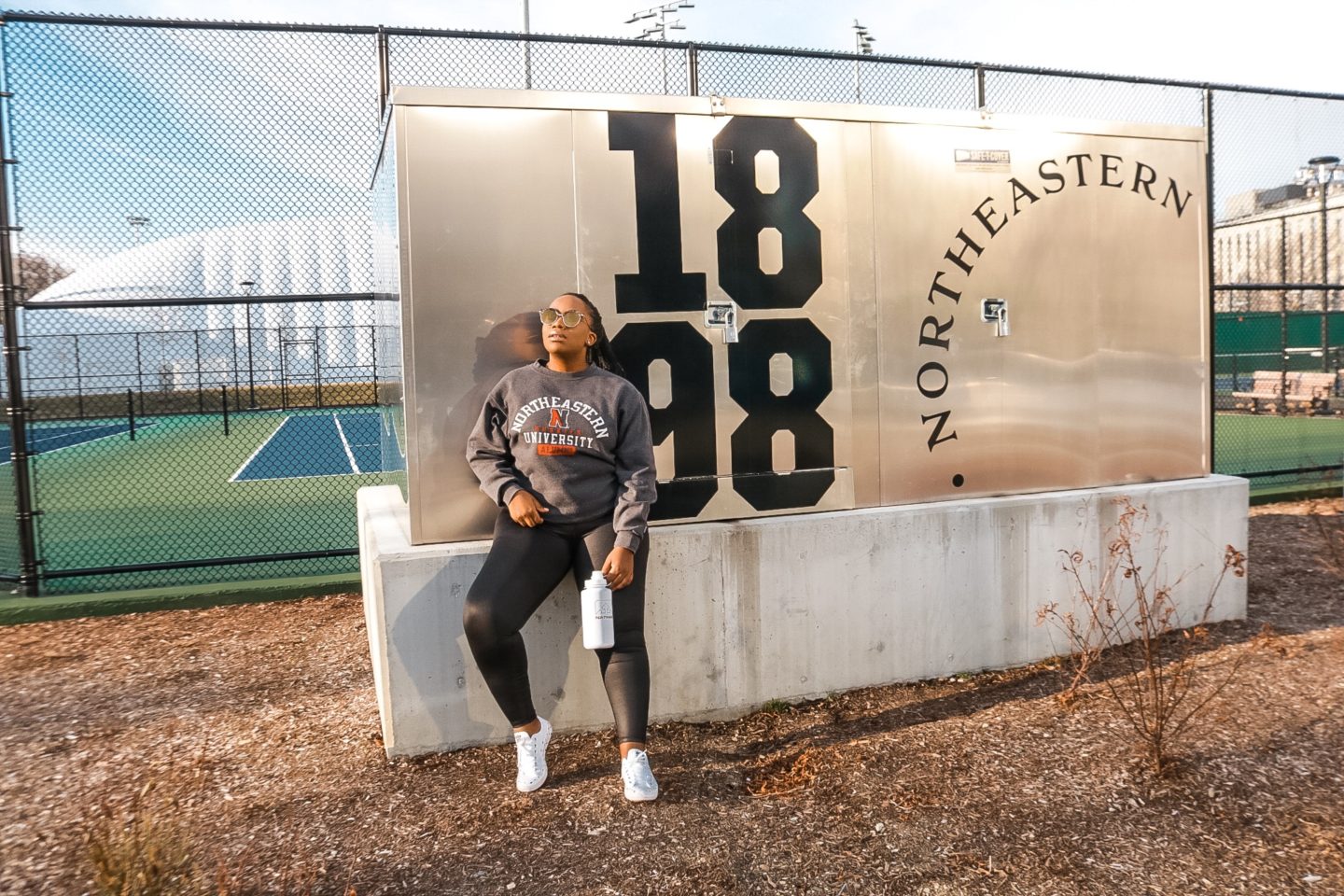 Boston based Fashion and travel blogger Binja in athleisure wear: Northeastern University sweatshirt and reebok workout tights.