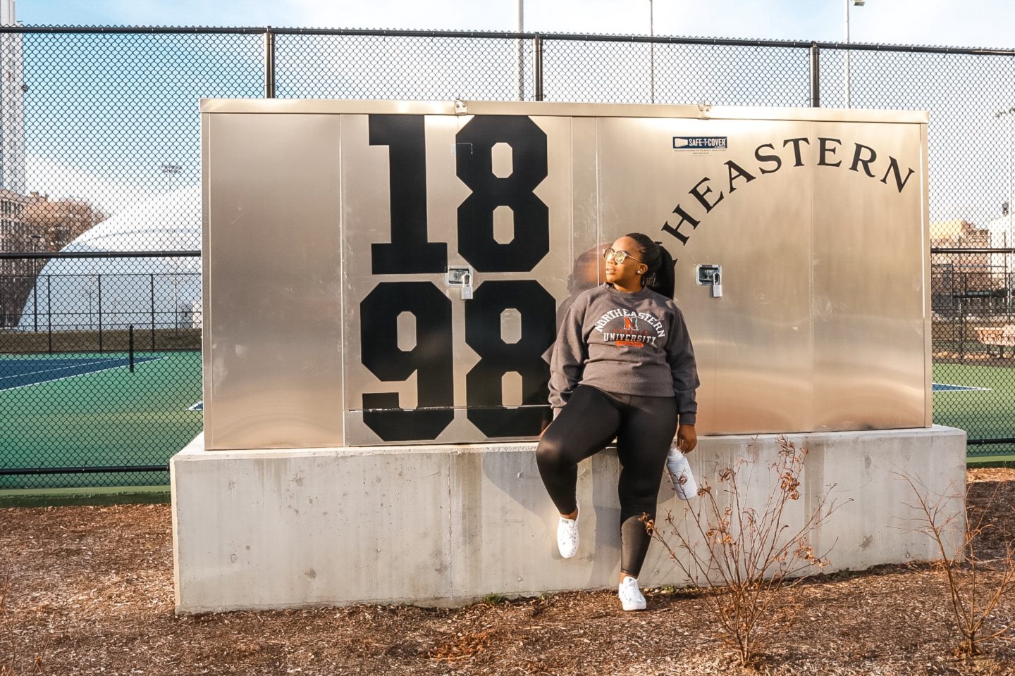 Boston based Fashion and travel blogger Binja in athleisure wear: Northeastern University sweatshirt and reebok workout tights.