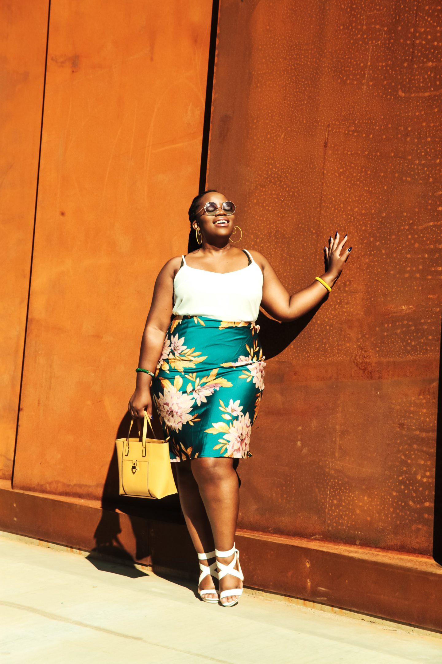 Binja the Africancocktail is wearing a floral Forever 21 skirt, a cream top, a yellow Primark bag and white Charlotte Russe heels